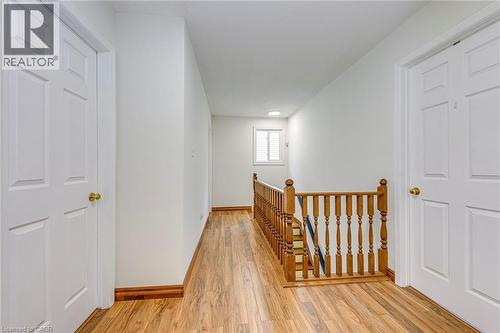 Hallway featuring wood-finish flooring, white paneled doors with brass hardware, and a wood banister - 43 Niska Drive, Waterdown, ON - Indoor Photo Showing Other Room