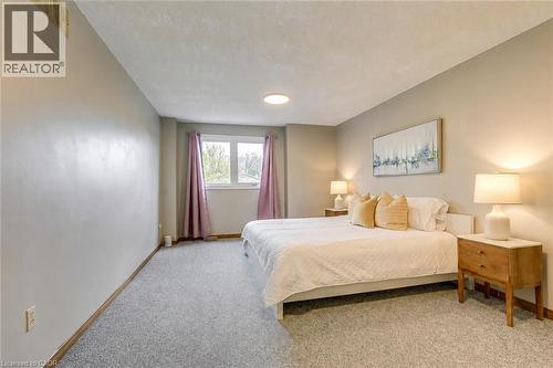 Spacious bedroom featuring light gray walls, textured gray carpet, a double window, and a ceiling-mounted light fixture - 43 Niska Drive, Waterdown, ON - Indoor Photo Showing Bedroom