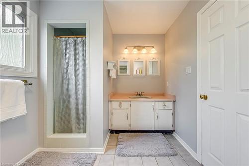 Bathroom featuring a built-in shower, window with privacy glass, vanity with single basin sink, and a four-light fixture - 43 Niska Drive, Waterdown, ON - Indoor