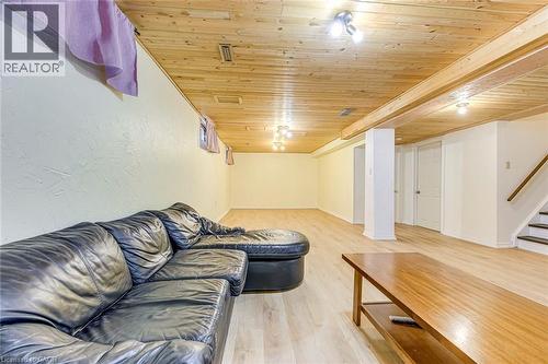 Spacious lower-level area featuring wood-finish flooring, a wood-paneled ceiling with track lighting and flush-mount fixtures, and a staircase with a wood handrail - 43 Niska Drive, Waterdown, ON - Indoor