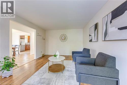 Light-filled living area featuring wood-finish flooring, neutral wall tones, and an arched doorway leading to a tiled dining space - 43 Niska Drive, Waterdown, ON - Indoor Photo Showing Living Room