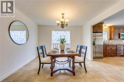 Dining area featuring tile flooring, a chandelier, and a window with a patterned privacy film - 43 Niska Drive, Waterdown, ON - Indoor Photo Showing Dining Room