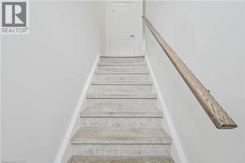 Carpeted staircase with a wood-finish handrail and crisp white trim - 720 Grey Street Unit# 34, Brantford, ON - Indoor Photo Showing Other Room