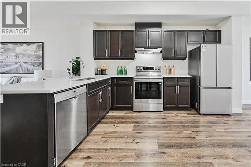 Modern kitchen featuring dark wood cabinetry, light-toned countertops, and wood-finish flooring - 720 Grey Street Unit# 34, Brantford, ON - Indoor Photo Showing Kitchen With Stainless Steel Kitchen