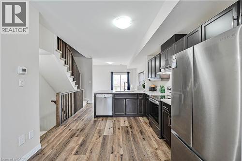 Open-concept kitchen with dark wood-finish cabinetry, stainless steel appliances, white countertops, and wood-finish flooring - 720 Grey Street Unit# 34, Brantford, ON - Indoor Photo Showing Kitchen
