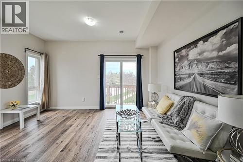 Spacious living area featuring wood-finish flooring, light-toned walls, and a large window - 720 Grey Street Unit# 34, Brantford, ON - Indoor