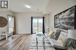 Spacious living area featuring wood-finish flooring, light-toned walls, and a large window - 