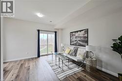 Spacious interior featuring wood-finish flooring, a sliding glass door providing access to an outdoor deck, recessed lighting, and bright white walls - 