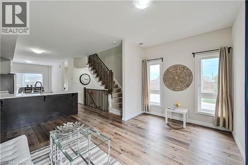 Open-concept living area with wood-finish flooring, white walls, and a staircase featuring dark wood railings - 720 Grey Street Unit# 34, Brantford, ON - Indoor