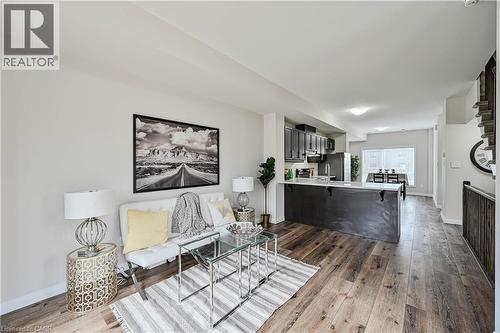 Open-concept living area featuring wood-finish flooring, a contemporary kitchen island with a light-toned countertop, dark cabinetry, and integrated stainless steel appliances - 720 Grey Street Unit# 34, Brantford, ON - Indoor Photo Showing Other Room