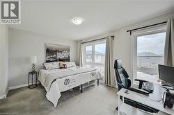 Carpeted bedroom featuring multiple windows, light neutral wall paint, and a flush mount ceiling light fixture - 