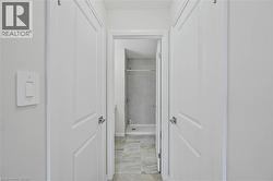 Hallway leading to a bathroom featuring a tile shower surround and a shower/tub combination - 