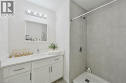 Bathroom featuring a white vanity with shaker-style cabinetry, a built-in sink, and a rectangular mirror - 