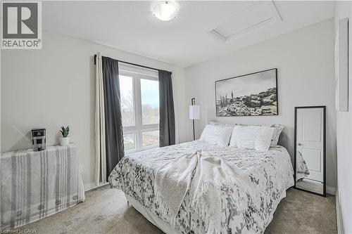 Light-filled bedroom featuring a large window, neutral wall paint, ceiling-mounted light fixture, and textured carpeting - 720 Grey Street Unit# 34, Brantford, ON - Indoor Photo Showing Bedroom