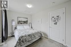 Carpeted room featuring a white paneled door, flush-mount ceiling light, and a window with dark curtains - 