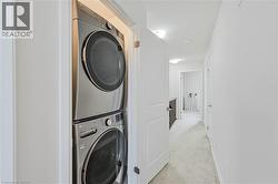 Hallway laundry closet featuring a stacked stainless steel washer and dryer - 