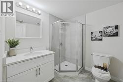 Modern bathroom featuring a white vanity with an integrated sink, a frameless rectangular mirror, and an enclosed corner shower with a glass door - 
