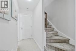 Carpeted staircase featuring a wood-finish handrail - 