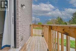 Private exterior balcony with wood decking and railing, gray brick exterior, and outdoor wall sconce - 