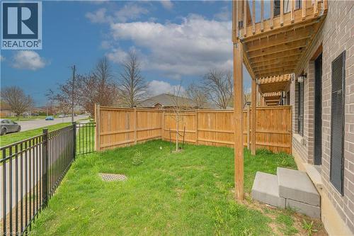 Private grassy yard featuring a wood privacy fence and black metal fencing - 720 Grey Street Unit# 34, Brantford, ON - Outdoor