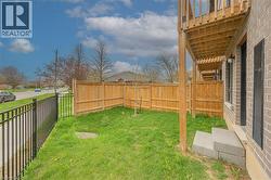 Private grassy yard featuring a wood privacy fence and black metal fencing - 