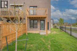 Brick exterior featuring two wooden balconies, a rear entry door with steps, a fenced yard, and an iron fence bordering the property - 