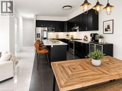 Contemporary kitchen featuring black cabinetry, stainless steel appliances, and a central island with a granite countertop - 