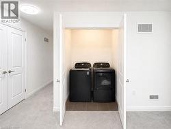 Dedicated laundry closet featuring a side-by-side washer and dryer, tile flooring, and overhead lighting - 