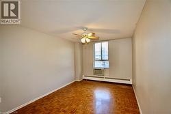Room featuring wood-finish parquet flooring, a ceiling fan with integrated lighting, and a large window - 