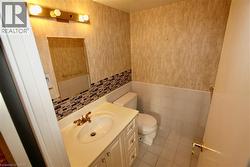 Bathroom featuring a vanity with an integrated sink, a mosaic tile backsplash, and a wall-mounted light fixture - 