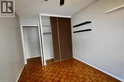 Room featuring parquet wood flooring, neutral wall paint, and a built-in closet with sliding wood-finish doors - 