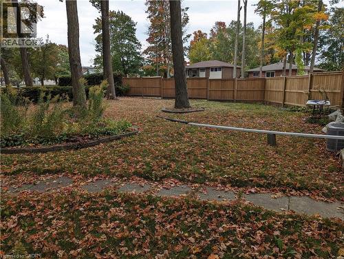 Expansive backyard featuring a wood fence, mature trees, and a concrete pathway - 462 Hazel Street, Waterloo, ON 