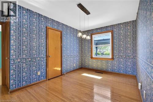 Room featuring wood-finish flooring, a single window with wood trim, and a modern chandelier - 525 East 16Th Street, Hamilton, ON - Indoor Photo Showing Other Room