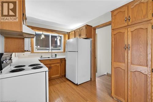 Kitchen featuring wood-finish cabinetry, white countertops, a white refrigerator, and wood-finish flooring - 525 East 16Th Street, Hamilton, ON - Indoor Photo Showing Kitchen With Double Sink
