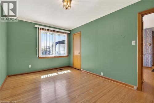 Room featuring wood-finish flooring, a window with vertical blinds, a ceiling-mounted light fixture, and a solid wood door - 525 East 16Th Street, Hamilton, ON - Indoor Photo Showing Other Room