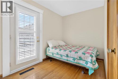 Room featuring a full-light door with integrated blinds, wood-finish flooring, and light-toned walls - 525 East 16Th Street, Hamilton, ON - Indoor Photo Showing Bedroom