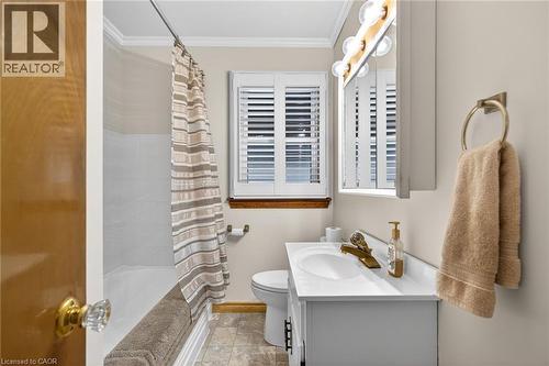 Compact bathroom with a single vanity, white countertop, and gold-finish faucet - 525 East 16Th Street, Hamilton, ON - Indoor Photo Showing Bathroom