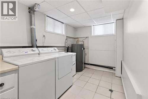 Laundry area featuring white appliances, a light-toned countertop, and white tiled flooring - 525 East 16Th Street, Hamilton, ON - Indoor Photo Showing Laundry Room