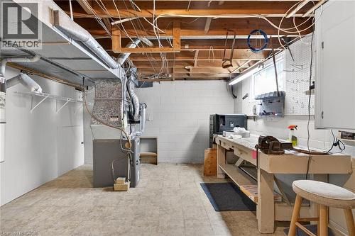 Basement area featuring a dedicated workbench, exposed ceiling joists, utility sink, and wall-mounted shelving - 525 East 16Th Street, Hamilton, ON - Indoor Photo Showing Basement