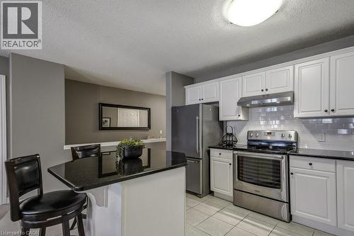 Kitchen featuring white shaker-style cabinetry, dark countertops, stainless steel appliances, and a white subway tile backsplash - 605 Welland Avenue Unit# 21, St. Catharines, ON - Indoor Photo Showing Kitchen