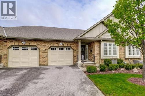 Brick exterior featuring two garage bays with paneled doors and window accents - 605 Welland Avenue Unit# 21, St. Catharines, ON - Outdoor With Facade