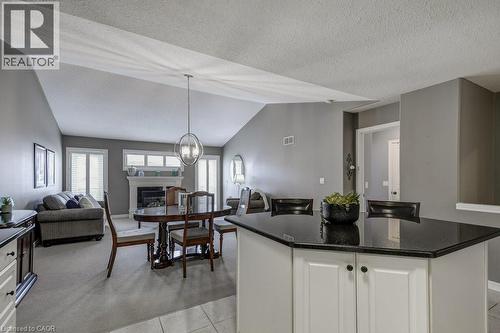 Open-concept living area featuring a vaulted ceiling and a central fireplace with a decorative mantel - 605 Welland Avenue Unit# 21, St. Catharines, ON - Indoor