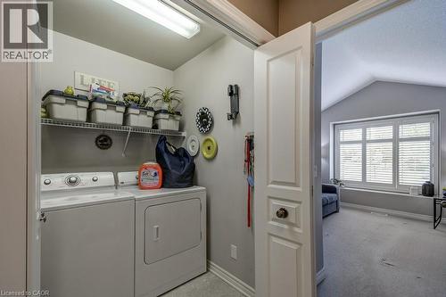 Dedicated laundry area featuring a white washer and dryer pair, overhead wire shelving, and overhead fluorescent lighting - 605 Welland Avenue Unit# 21, St. Catharines, ON - Indoor Photo Showing Laundry Room