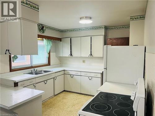 U-shaped kitchen featuring white cabinetry, white countertops, a double basin stainless steel sink, and a white electric range - 157 Schweitzer Street, Kitchener, ON - Indoor Photo Showing Kitchen With Double Sink