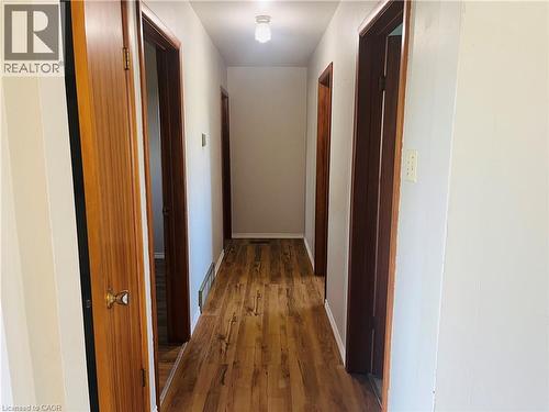 Hallway featuring wood-finish flooring, light neutral wall paint, recessed lighting, and multiple wood-paneled doors with brass hardware - 157 Schweitzer Street, Kitchener, ON - Indoor Photo Showing Other Room