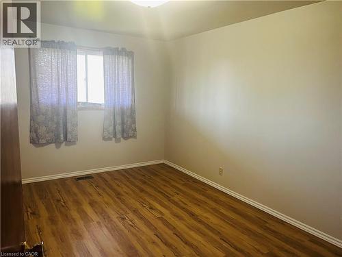 Room featuring wood-finish flooring, a window with trim, light-colored walls, and white baseboards - 157 Schweitzer Street, Kitchener, ON - Indoor Photo Showing Other Room