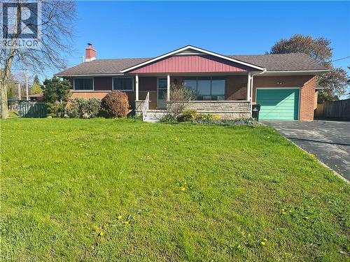 Brick ranch-style residence featuring a prominent front porch with stone detailing, a teal-colored garage door, and a paved driveway - 157 Schweitzer Street, Kitchener, ON - Outdoor