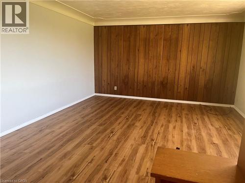 Spacious room featuring wood-finish flooring, a prominent wood paneled accent wall, and light-toned painted walls - 157 Schweitzer Street, Kitchener, ON - Indoor Photo Showing Other Room