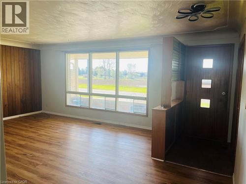 Spacious room featuring wood-finish flooring, a large multi-pane window, and a wood panel accent wall - 157 Schweitzer Street, Kitchener, ON - Indoor Photo Showing Other Room