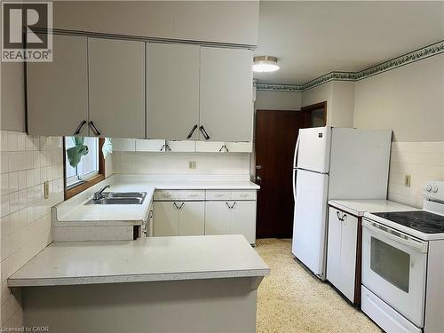 White cabinetry and countertops define this kitchen space, featuring a double basin sink beneath a window - 157 Schweitzer Street, Kitchener, ON - Indoor Photo Showing Kitchen With Double Sink